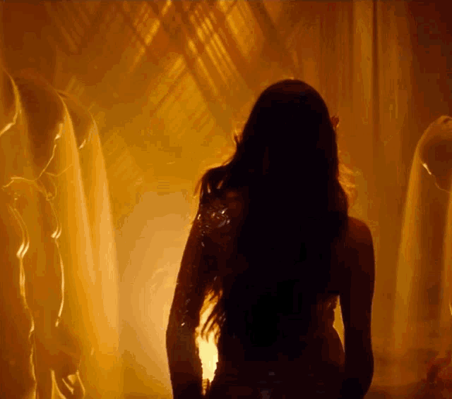 a silhouette of a woman with long hair standing in a dark room