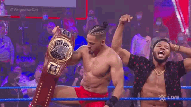 a man without a shirt is holding a championship belt in front of a crowd .