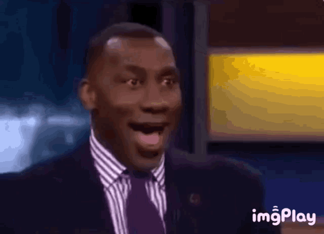 a man in a suit and tie is making a surprised face while talking on a television show .
