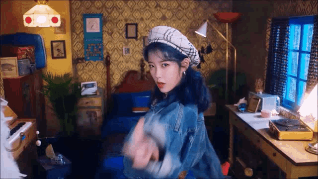 a woman with blue hair is wearing a beret and a denim jacket .