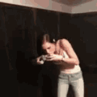a woman in a crop top and jeans is standing in a room .