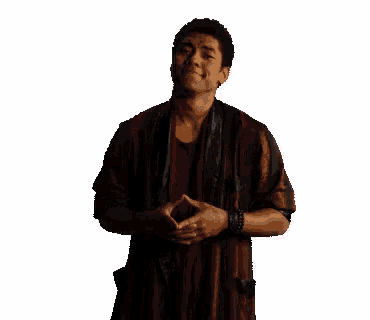a man in a red and black striped robe is standing with his hands folded