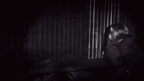 a black and white photo of a young girl in a dark room .