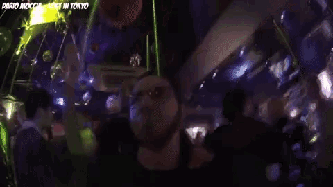a group of people are dancing in a dark room with the words dario mocchi lost in tokyo on the bottom right