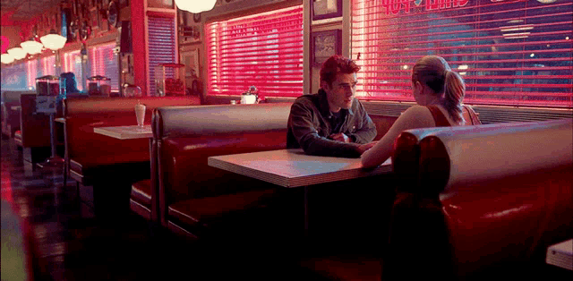 a man and a woman are sitting at a diner table