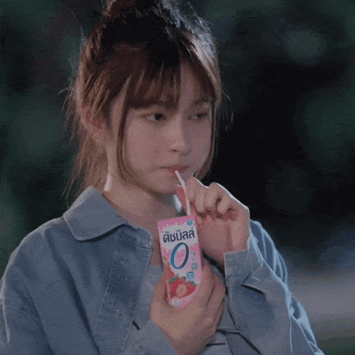 a girl drinking from a carton that says 0