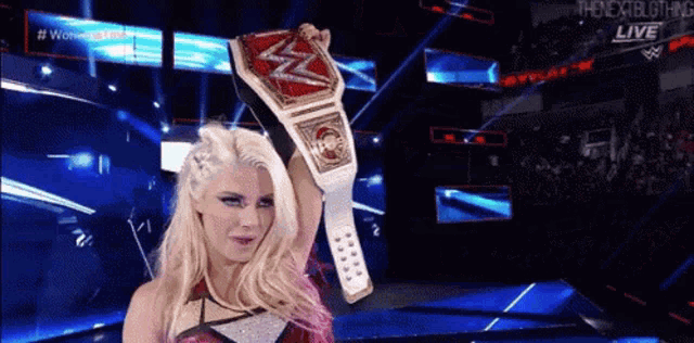 a woman is holding a wrestling championship belt over her head