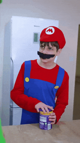 a boy dressed as mario is holding a can