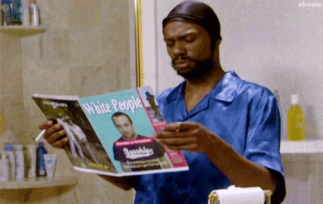 a man is reading a white people magazine in a bathroom