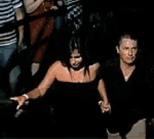 a woman in a black strapless top is standing in a crowd of people