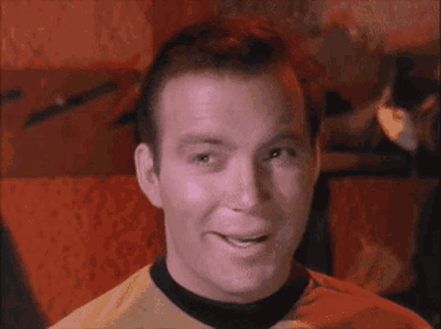 a man in a yellow shirt with a black collar smiles