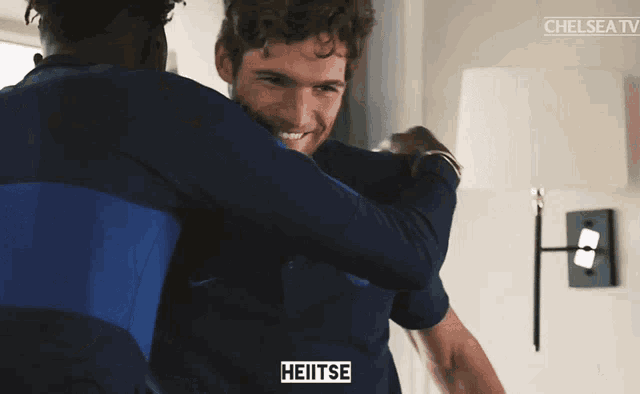 a man hugging another man with the word heitse on his chest