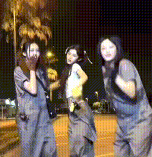 a group of three women are standing next to each other in a parking lot at night .