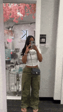 a woman taking a picture of herself in a mirror with a sign that says k on it