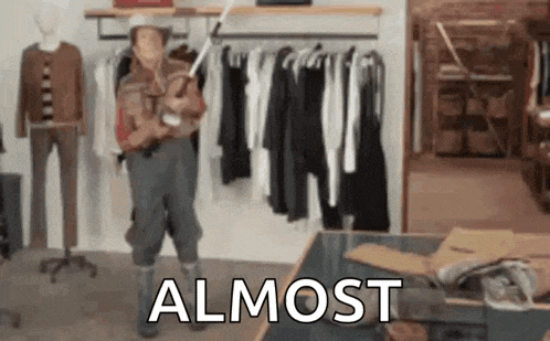 a man in a cowboy hat is standing in a clothing store holding a fishing rod .