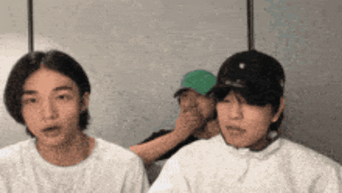 two men wearing white shirts and hats are sitting next to each other .