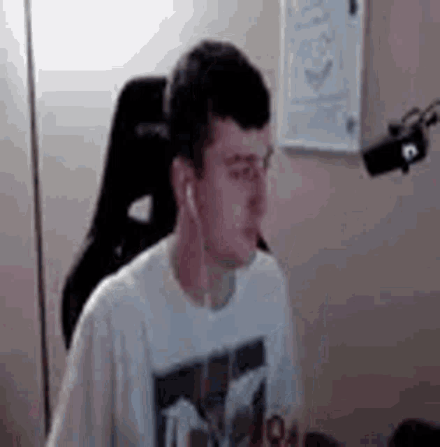 a man wearing headphones is sitting in a chair in front of a microphone in a room .