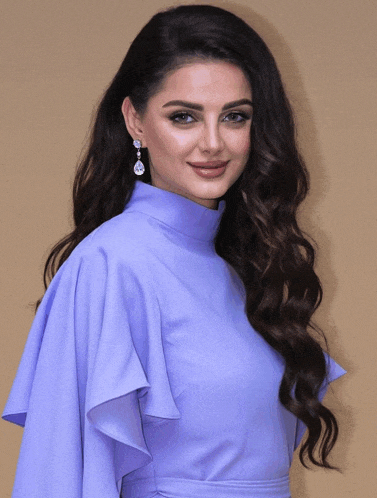 a woman wearing a purple dress and earrings is smiling
