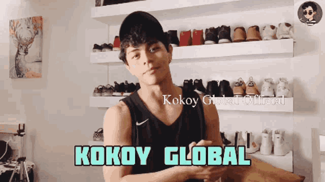 a man standing in front of a wall of shoes with kokoy global written on the bottom