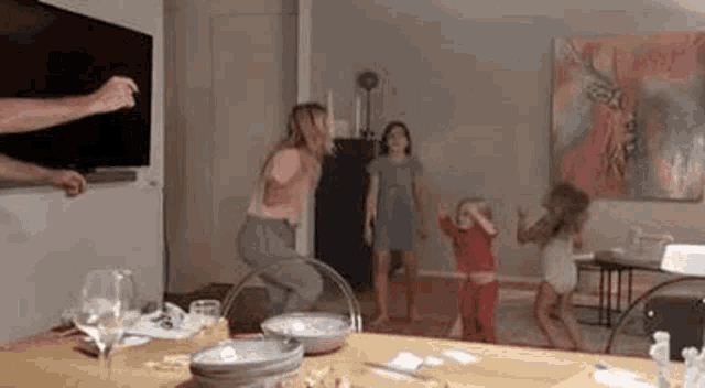 a group of people are standing around a table dancing .