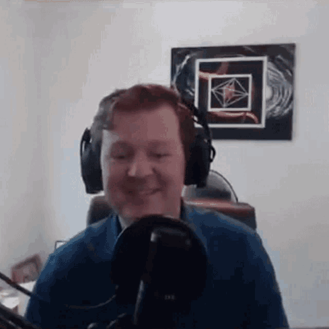 a man is wearing headphones and smiling in front of a microphone .
