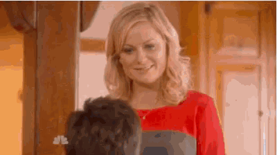 a woman in a red shirt is standing next to a man in a room .