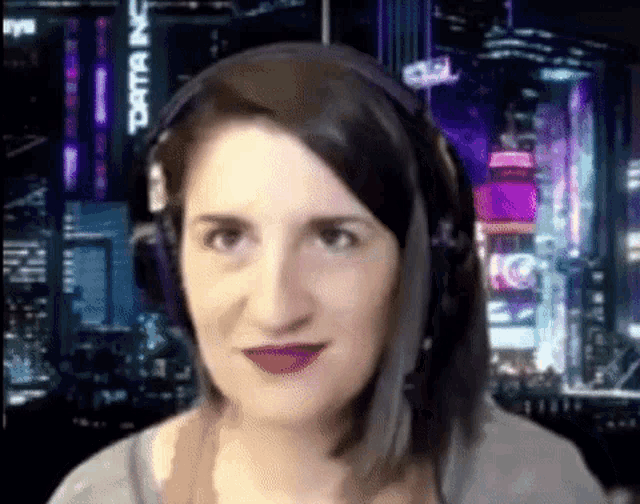 a woman wearing headphones and purple lipstick is standing in front of a city skyline .