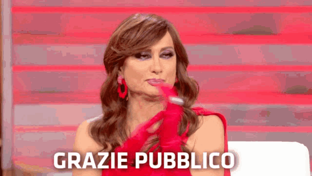 a woman in a red dress is sitting in front of a sign that says " grazie pubblico "