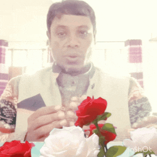 a man sitting in front of a vase of roses with a shot watermark