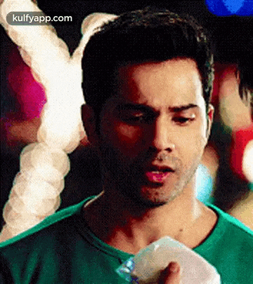 a man in a green shirt is holding a plastic bag and looking at it .