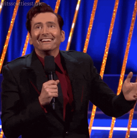 a man in a suit and tie is holding a microphone and smiling ..