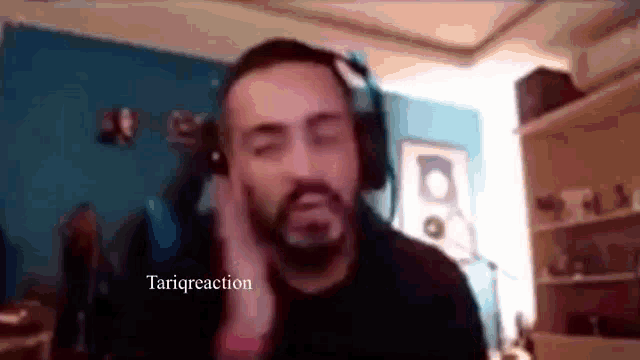 a man with a beard wearing headphones is sitting in front of a computer screen .