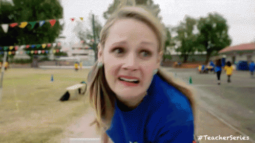 a woman in a blue shirt is making a funny face while running on a track .