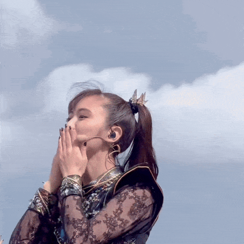a woman wearing a microphone and a ponytail looks up at the sky