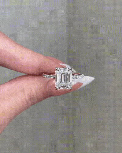 a woman is holding a ring with a large diamond in it