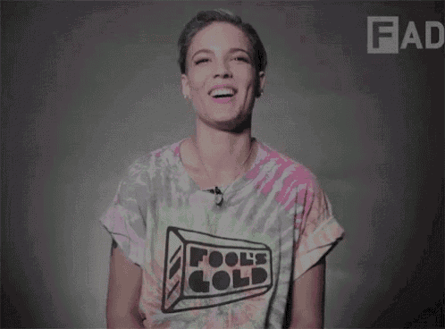 a woman wearing a tie dye t-shirt that says fool 's gold is laughing .