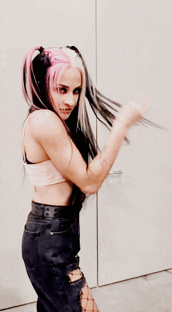 a woman with long black and pink hair is standing in front of a wall