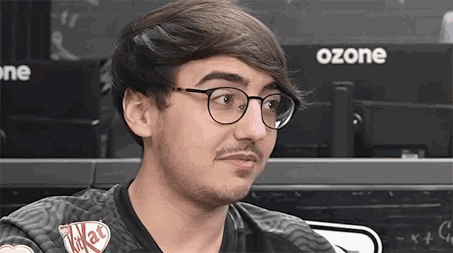 a man wearing glasses and a kitkat shirt