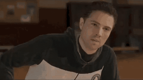 a man in a hoodie is looking at the camera in a classroom .