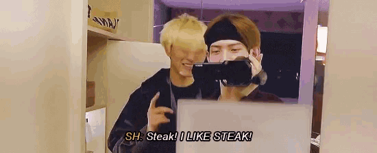 two men are taking a picture of themselves in a mirror and one of them says " steak ! i like steak "