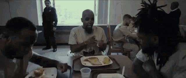 a group of men are sitting at a table eating food