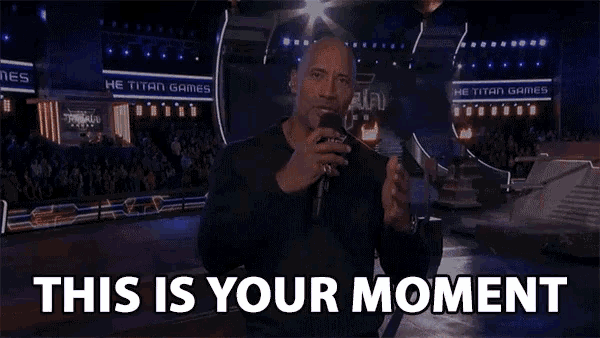 a man speaking into a microphone with the words " this is your moment " above him