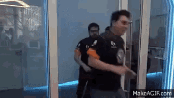 two men are walking through a glass door with makeagif.com written on the bottom