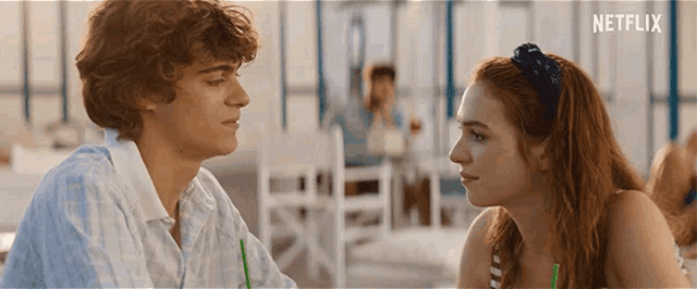 a man and a woman are looking into each other 's eyes while sitting at a table .