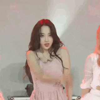 a woman in a pink dress is dancing on a stage in front of a red light .