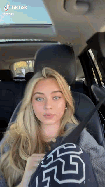 a young woman is sitting in the back seat of a car with a seat belt on .
