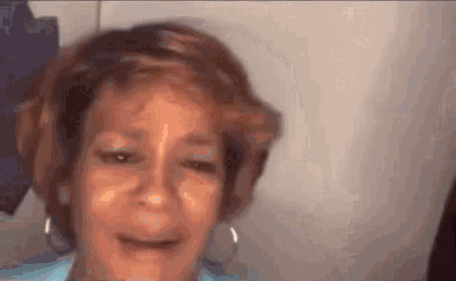 a woman with short hair and hoop earrings is crying .