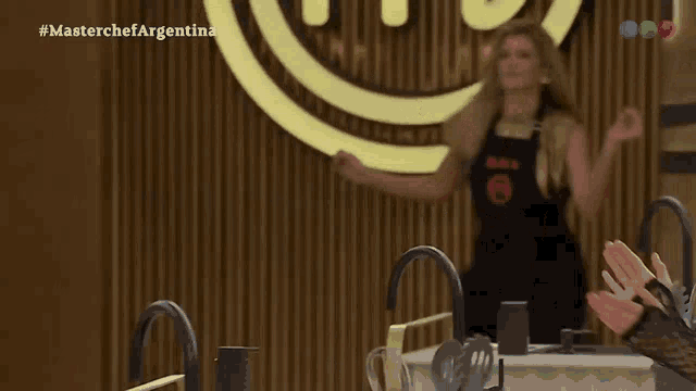 a woman is dancing in front of a masterchef argentina logo
