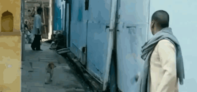 a man walking down a narrow street with a dog