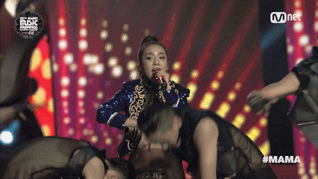 a woman singing into a microphone on a stage with #mama written below her